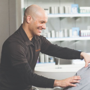 Photo of a smiling man, products on a shelf in the background