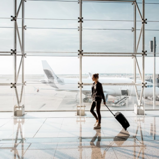 Woman walking through an airport, pulling a suitcase